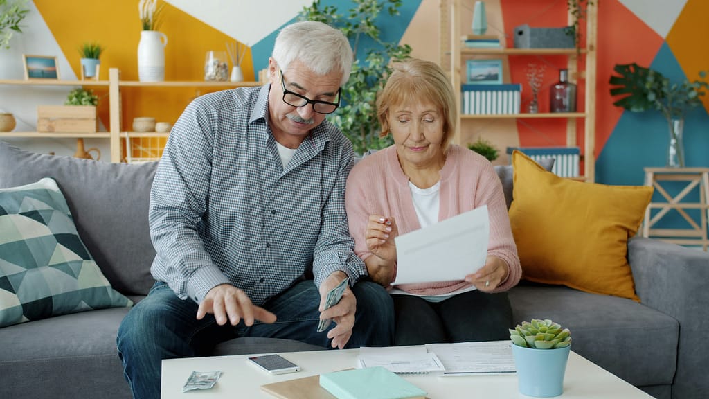 Older couple reviewing financial documents and paperwork together at home, discussing trust funding and estate planning
