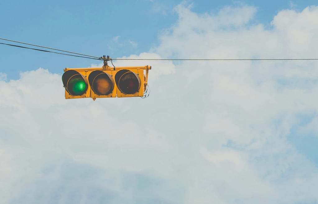 A green pedestrian walk signal glowing against a blue sky, symbolizing the green flags in a Power of Attorney checklist.