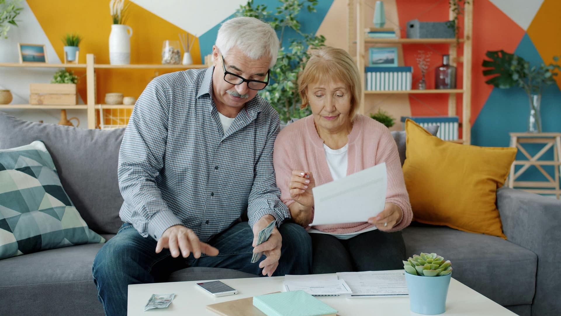 Older couple reviewing financial documents and paperwork together at home, discussing trust funding and estate planning